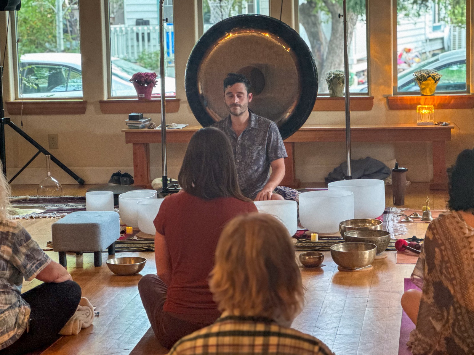 Zach Lee seated at the gong with a small group gathered around singing bowls.